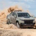 A tan 2021 Chevy Colorado ZR2 is shown off-roading in a dusty desert area.