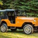 A orange 1955 Jeep CJ-5 is parked in the grass after leaving a Jeep Wrangler dealer near Lexington.
