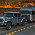 A silver 2019 used Jeep Gladiator is towing an Airstream trailer.