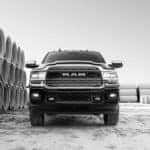 A black and white photo shows a black 2019 Ram 2500 surrounded by concrete pipes and shown from a low angle.