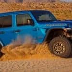 A blue 2021 Jeep Wrangler Rubicon 392 from a Lexington Jeep dealer is off-roading in the sand.