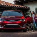 A red 2018 Chrysler Pacifica is parked in a drivway as a family and dog get out.