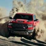 A red 2021 Ram 1500 TRX is off-roading through a sandy desert.