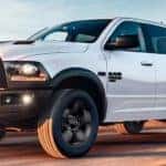 A white 2020 Ram 1500 is shown from the side driving after leaving a used Ram truck dealership in Lexington.