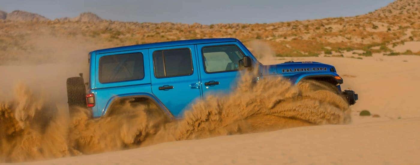 A blue 2021 Jeep Wrangler Rubicon 392 is shown off-roading in a sandy desert.
