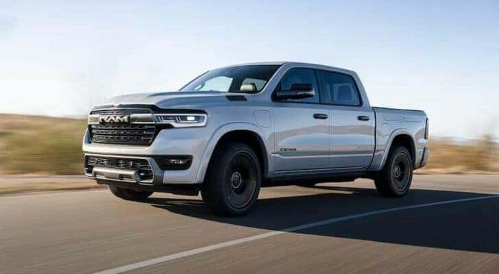 A white 2025 Ram 1500 Ramcharger is shown driving from a dealer with a Ram 1500 for sale near Independence.