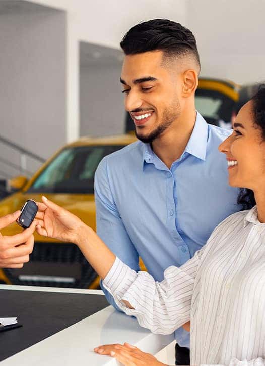 Leasing versus Buying a Chrysler Dodge Jeep RAM at Delaney CDJR of DuBois in DuBois, PA | Salesman handing over new car keys to couple