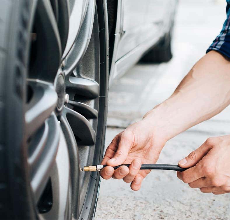 Tire Pressure Information at Delaney CDJR of DuBois in DuBois, PA | Person putting air into tire using a tire pressure tool