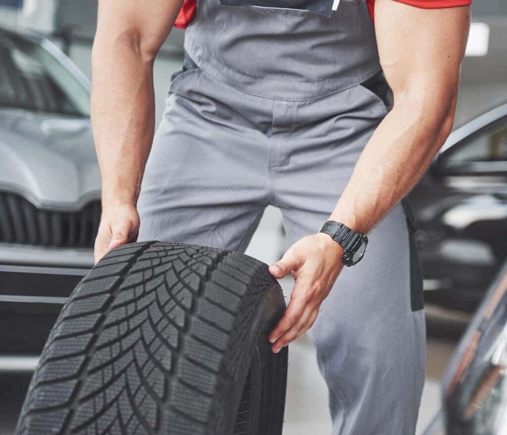 How to check your tires' health at Delaney Hyundai of Dubois | Mechanic rolling old used tire on the floor