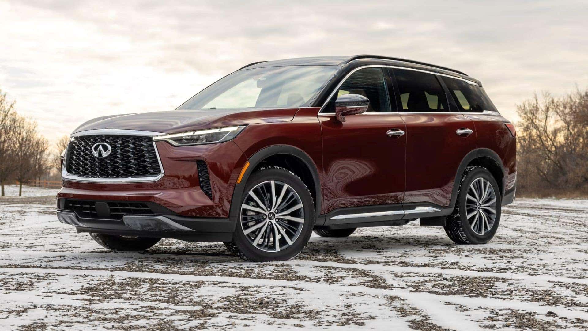 A Burgundy 2023 INFINITI QX60, Parked Under Sunlight In Snowy Terrain