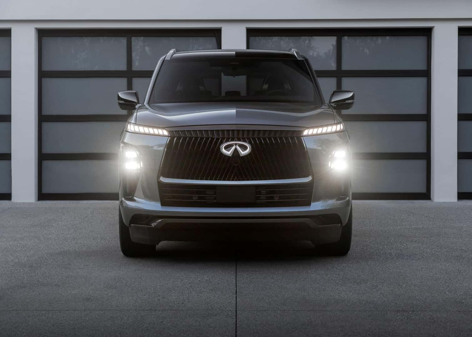 The 2025 INFINITI QX80's Bright Headlights Beaming, Parked Perfectly In A Petite Driveway
