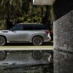 The 2025 INFINITI QX80 Side Profile, Parked Near A Water Pool That Reflects It Majesty And Value
