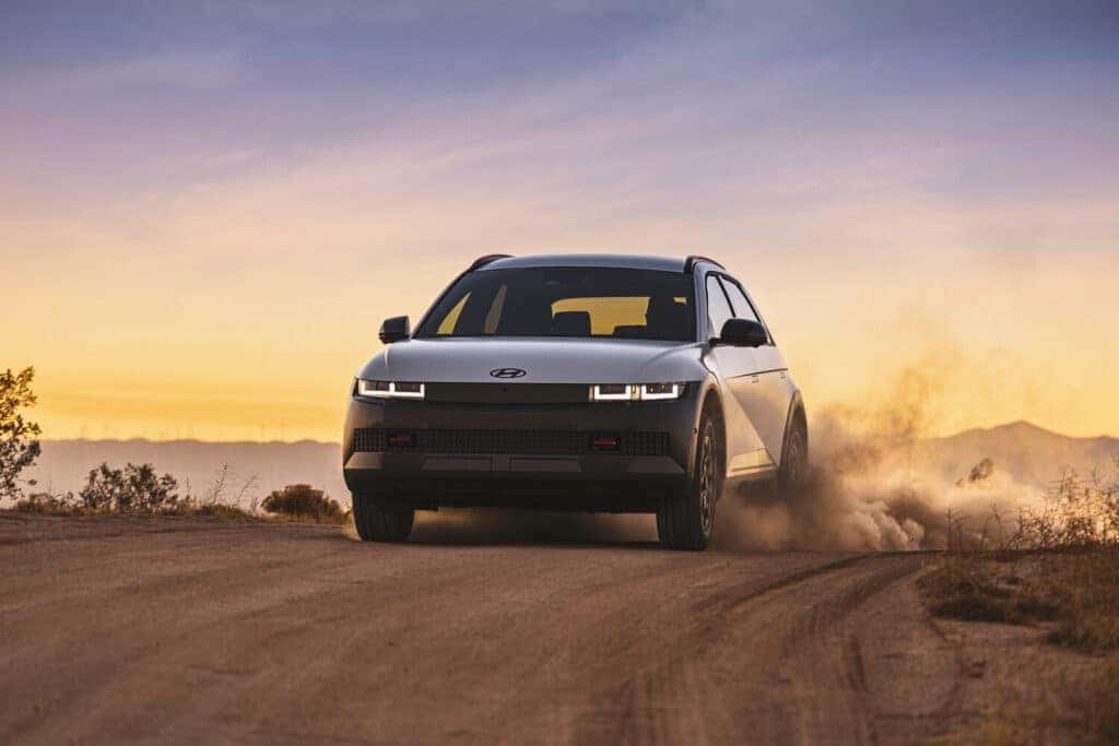 A 2025 IONIQ 5 XRT navigating a rugged dirt road, showcasing its versatility and off-road capability.