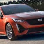 An orange 2020 Cadillac CT5-V, which is a good example to look at for the cost of owning a luxury car, is on a road with dark trees behind it outside of Fort Worth, TX.