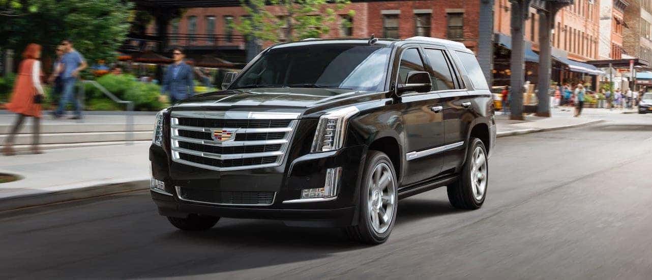 A black 2020 Cadillac Escalade is driving in downtown Fort Worth, TX.