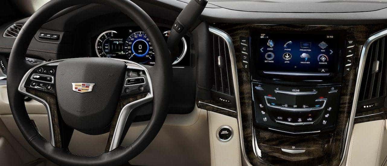 The tan, black and wood dashboard and steering wheel are shown in a 2020 Cadillac Escalade in Fort Worth, TX.