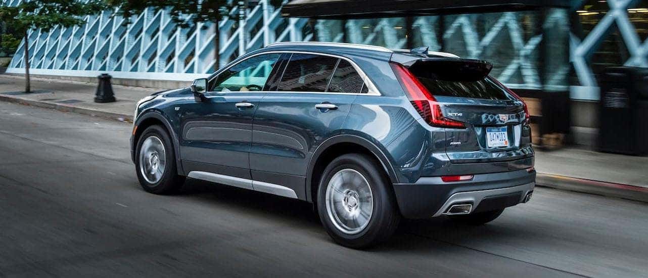 A blue 2020 Cadillac XT4, which wins when comparing the 2020 Cadillac XT4 vs 2020 BMW X1, is driving on a city street.