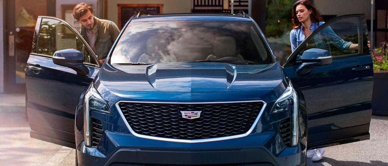 A couple is getting into a blue 2020 Cadillac XT4, shown from the front.