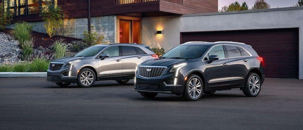 Two 2020 Cadillac XT5s are parked in a driveway outside Fort Worth, TX, one silver Sport and one black Premium Luxury.