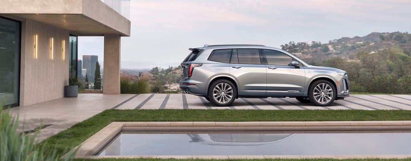 A silver 2020 Cadillac XT6 is parked in front of an upscale home and reflecting pool near Fort Worth, TX.