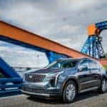 A blue 2019 used Cadillac XT4 is driving over a blue and orange bridge.