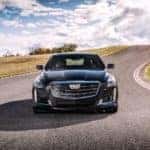 A common sight at a used luxury car dealer near you, a black 2017 Cadillac CTS, is shown from the front driving on an empty highway.