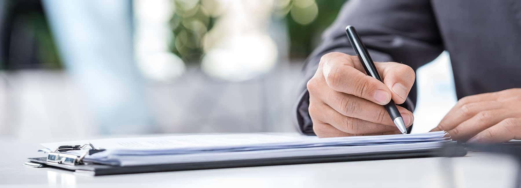Person Signing Documents in Clipboard