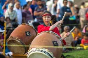 Japanese Festival woman drumming in the park for a crowd of people