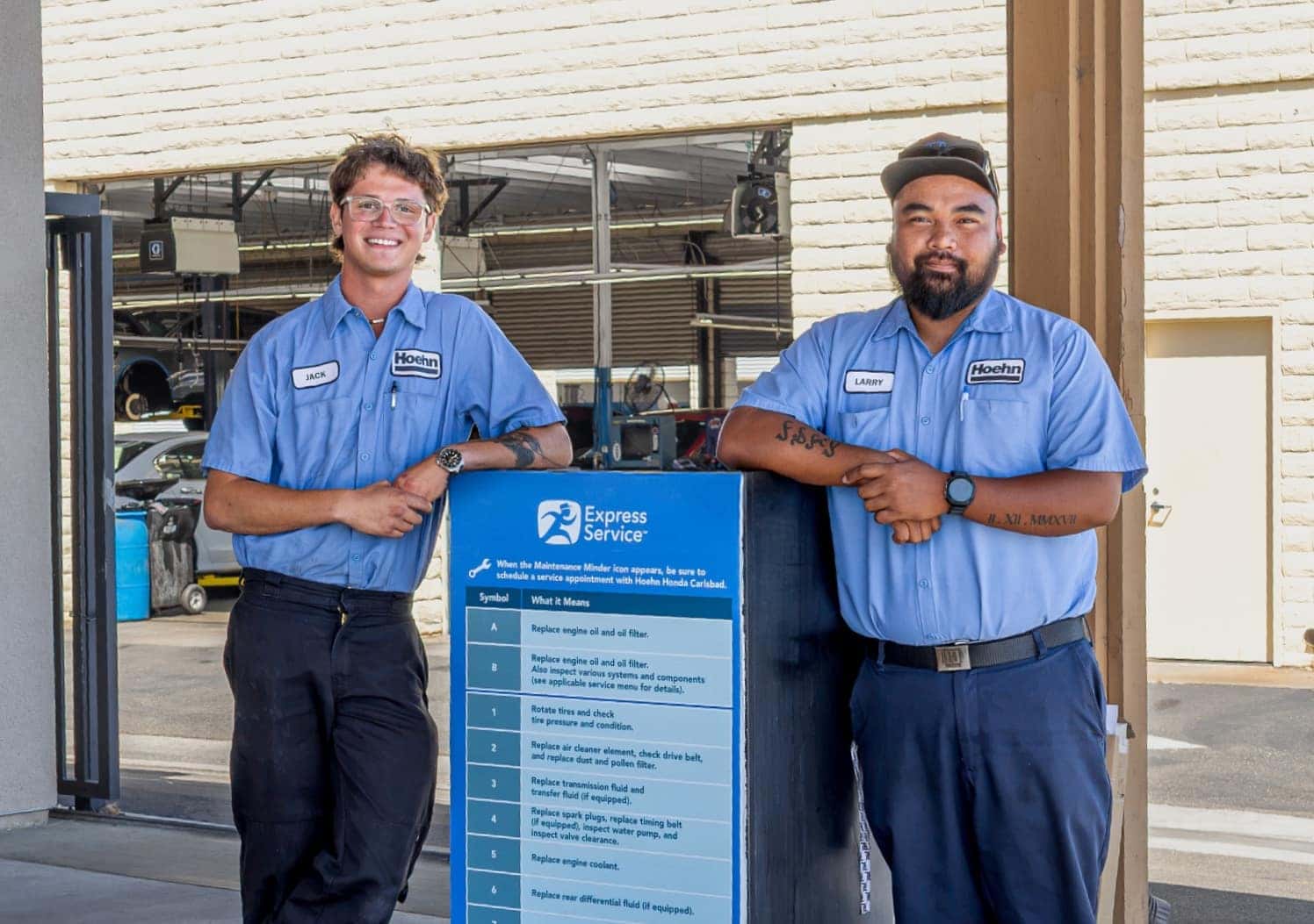 Two Hoehn Honda technicians beside the Express Service menu board