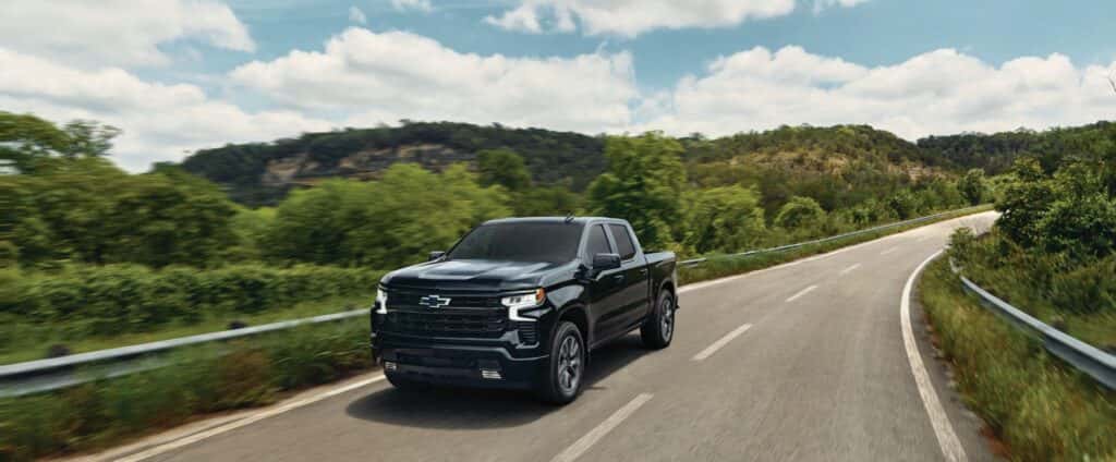 2026 Silverado 1500 RST driving down the open summer road.