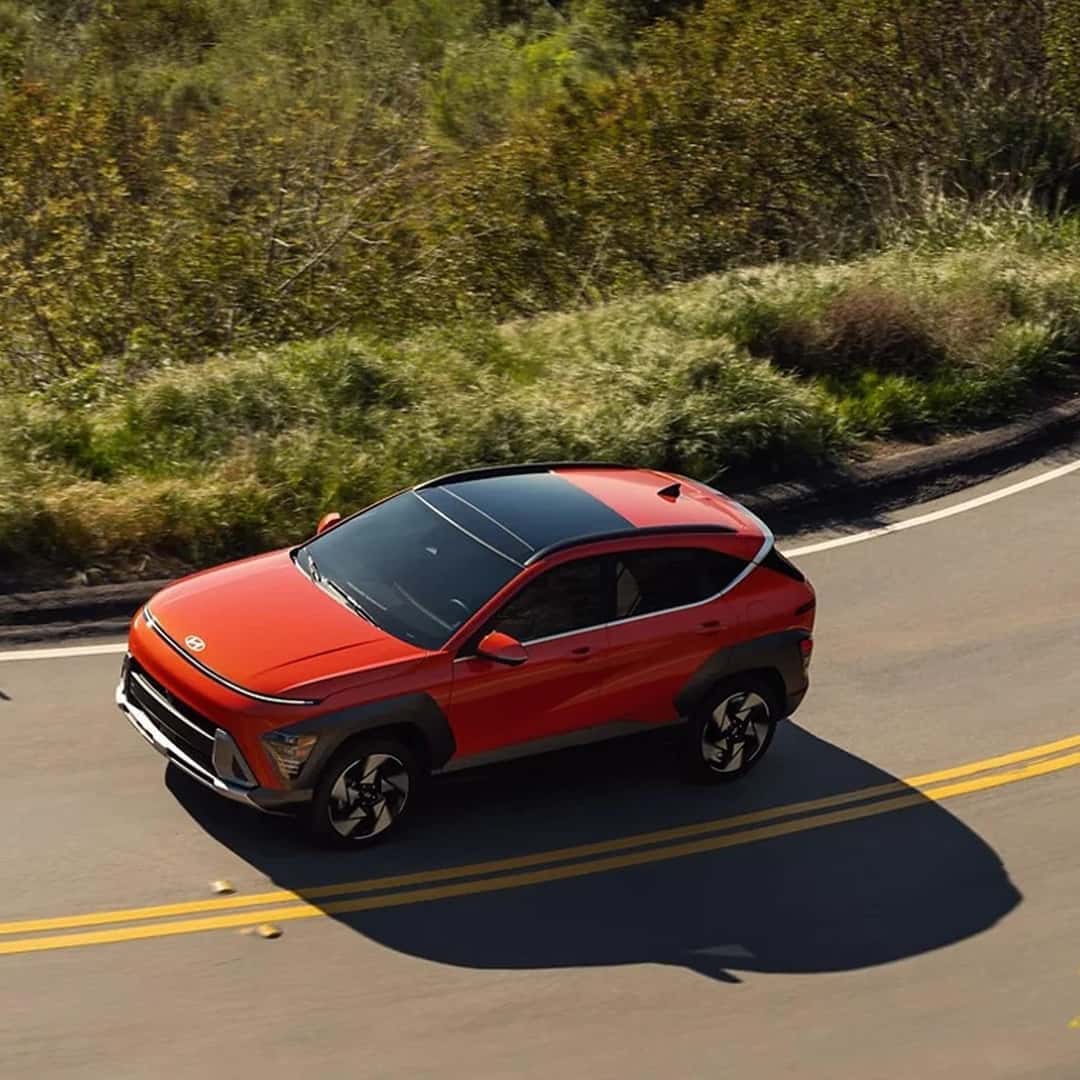 orange 2025 hyundai kona driving on road