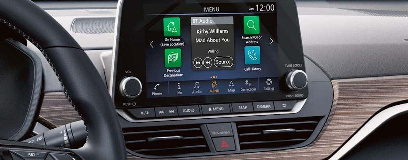 The infotainment screen and wood paneled dashboard is shown in a 2021 Nissan Altima.