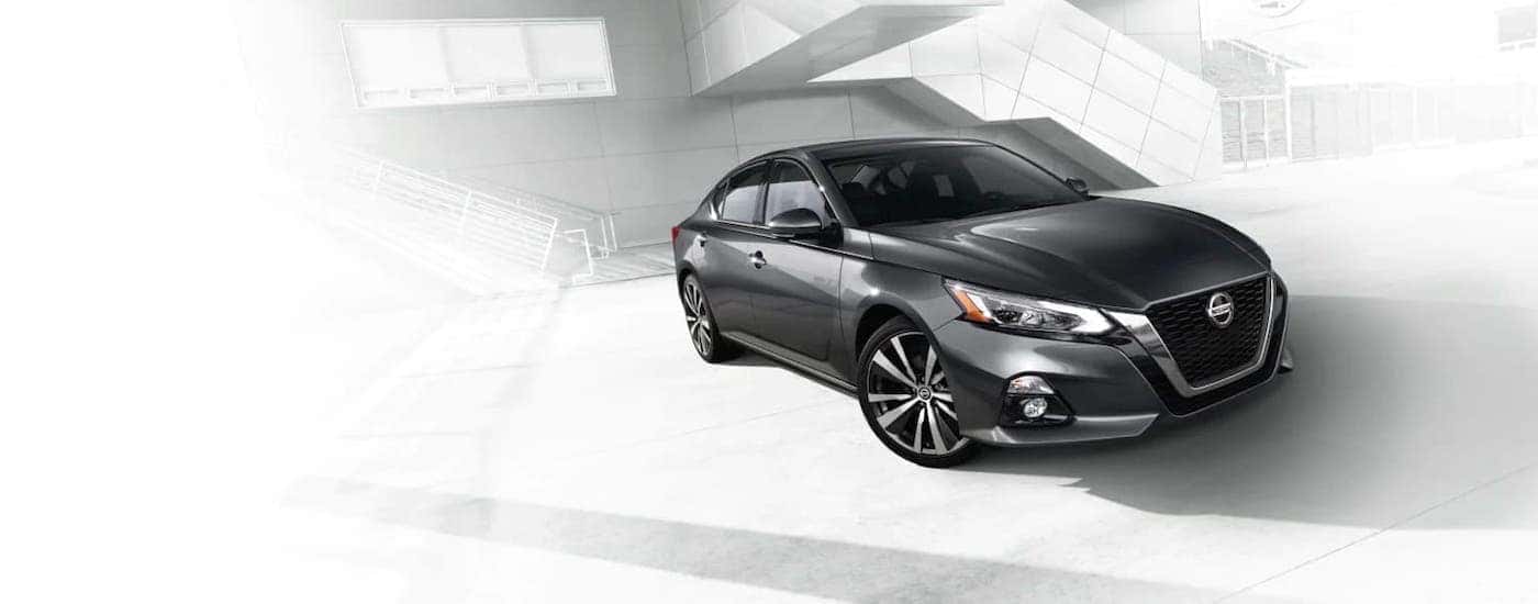 A gray 2021 Nissan Altima is on a washed out background image of a building with stairs.