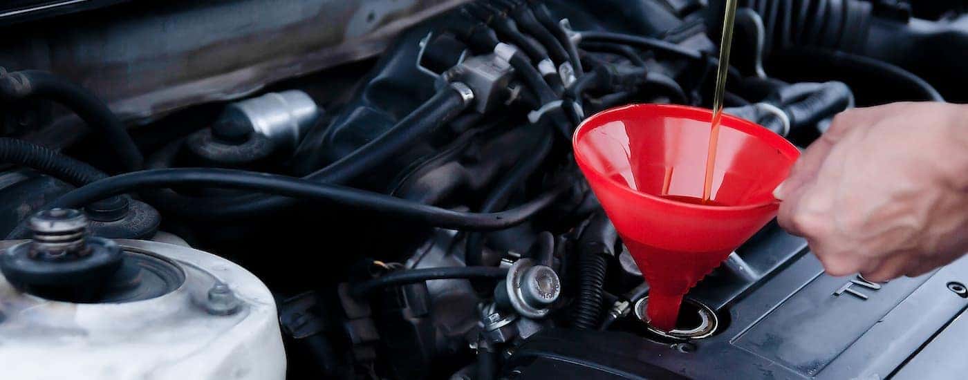 A closeup shows oil poured into a funnel at a Nissan service.