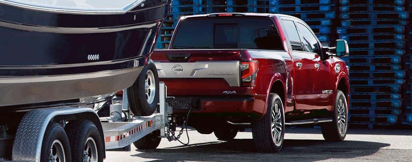 A red 2021 Nissan Titan XD is shown from behind while towing a boat.