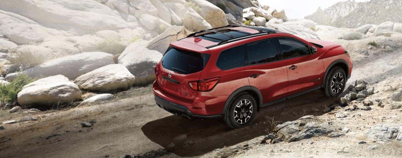 A red 2020 Pathfinder, similar to the upcoming 2021 Nissan Pathfinder, is off-roading on a dirt trail.