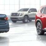 A blue car, red SUV. and White 2021 Nissan Titan are in a Tullahoma Nissan dealer.