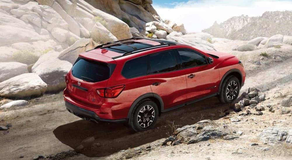 A red 2021 Nissan Pathfinder is shown from the side driving up a dirt path.