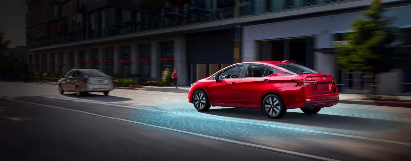 A red 2021 Nissan Versa is shown from the side driving through the city.