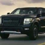 A black 2021 Nissan Titan is shown driving down a two lane road at sunset aftr leaving a Tennessee Nissan dealer.
