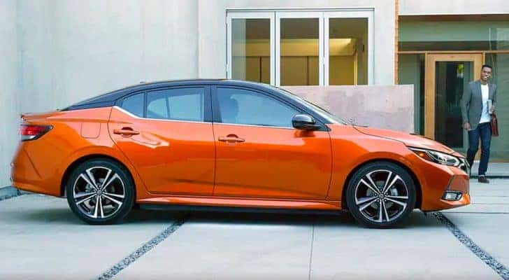 A man is shown approaching an orange 2021 Nissan Sentra.