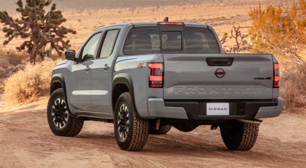 A grey 2022 Nissan Frontier is shown from the rear parked in a desert.