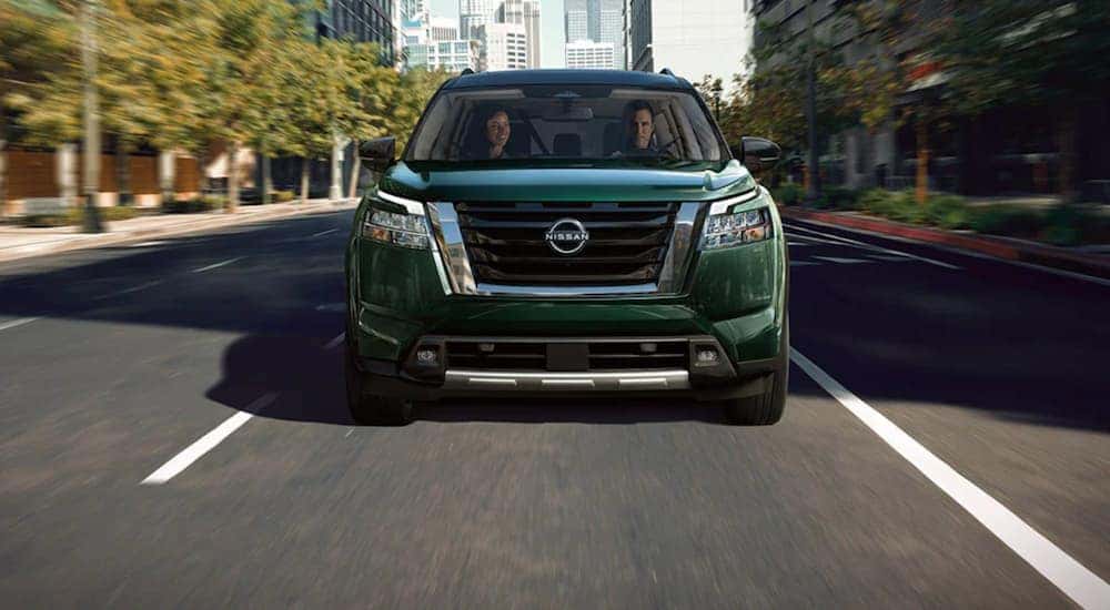 A green 2022 Nissan Pathfinder is shown from the front driving through a city.