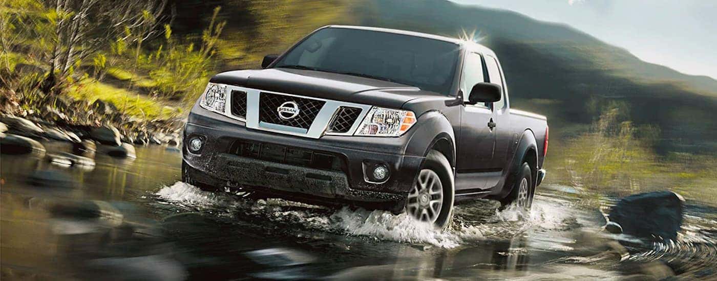 A grey 2021 Nissan Frontier is shown driving through a creek.