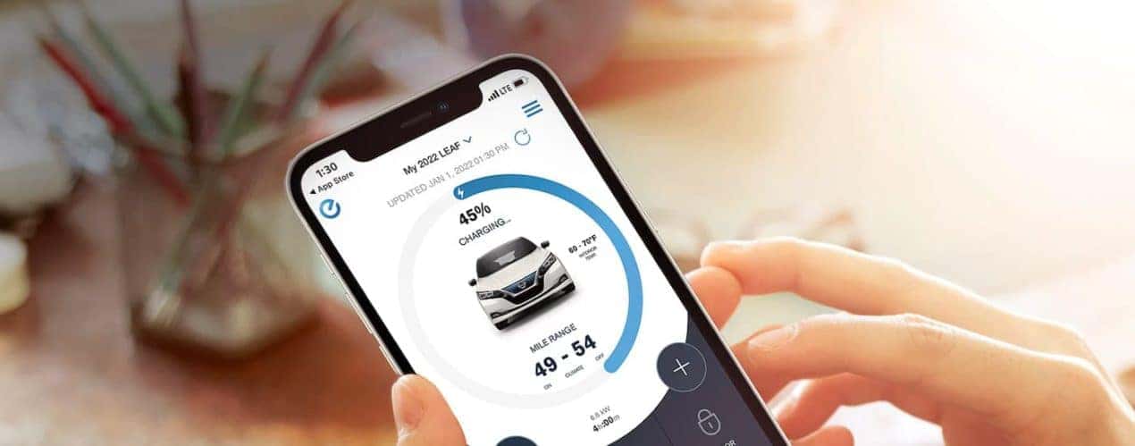 A close up shows the charging status on a smart phone app for a white 2022 Nissan LEAF.