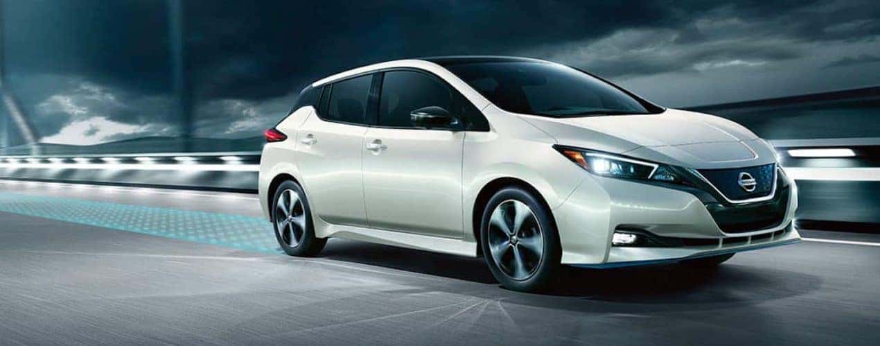 A white 2022 Nissan LEAF is shown from the side driving over a bridge.