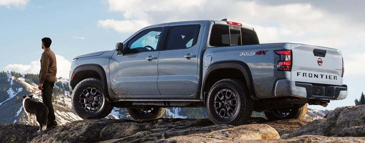 A grey 2022 Nissan Frontier is shown from the side parked in the mountains.