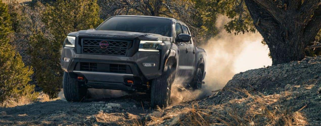 A grey 2022 Nissan Frontier is shown from the front off-roading in the mountains.