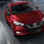 A red 2020 Nissan Versa is shown driving on a highway at night.
