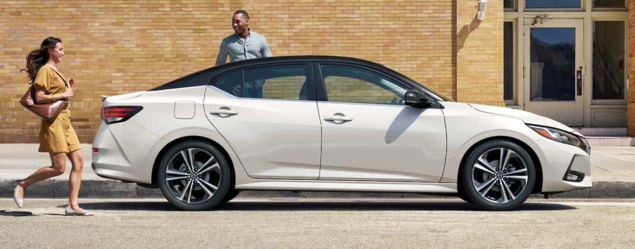 A white 2022 Nissan Sentra is shown from the side parked in front of a city building.